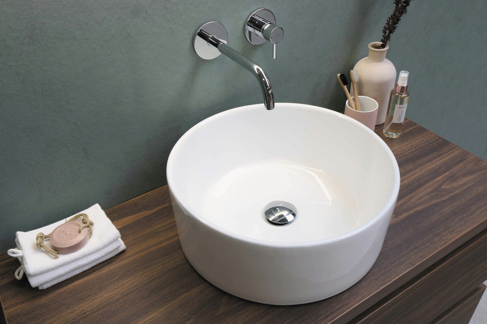 A modern wall-mounted bathroom faucet over a round basin